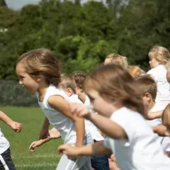 Bambini in corsa su un prato verde, felici di fare sport.