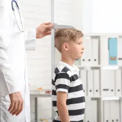 Un bambino viene misurato da un medico. La domanda "quanto sarà alto mio figlio" aleggia nell'aria mentre si attende il risultato.