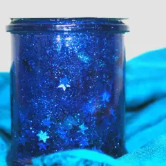 Barattolo della calma blu scintillante con stelle cadenti, avvolto in un tessuto turchese.