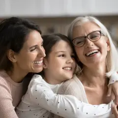 Tre generazioni di donne sorridono felici, un abbraccio che ricorda le più belle canzoni per la festa della mamma.