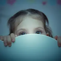 Occhi spaventati di un bambino di 2 anni che si sveglia piangendo disperato nel buio.