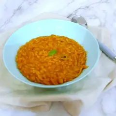 Un piatto di pastina al pomodoro, gustosa e profumata, guarnita con una fogliolina verde.