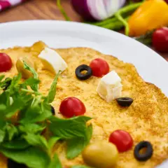 Frittata per bambini, colorata con pomodorini, olive, cubetti di formaggio e rucola. Un piatto gustoso e invitante.