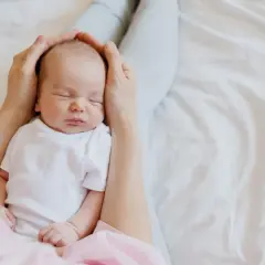 Mani che accarezzano la testa di un neonato addormentato. Il dolce rumore phon bambini lo culla nel sonno.