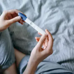 Mani che tengono un test di gravidanza, sperando in trucchi per rimanere incinta del secondo figlio.