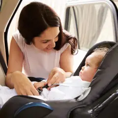 Mamma controlla la posizione corretta neonato nell'ovetto, assicurandosi che sia ben allacciato per un viaggio sicuro.