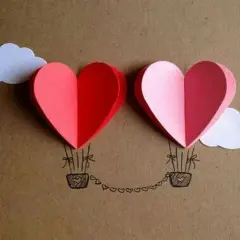 Lavoretto festa della mamma infanzia: due mongolfiere a forma di cuore rosse e rosa, con nuvole bianche e cesti disegnati.