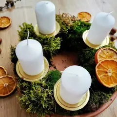 Corona dell'avvento fai da te con muschio, candele bianche, fette d'arancia essiccata e nocciole.