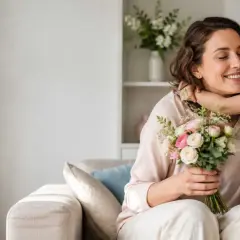 Bambina bacia la mamma che tiene un mazzo di fiori. Un momento dolce che ricorda quand'è la festa della mamma.