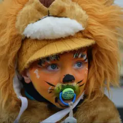 Bambino con trucco carnevale facile da leone, con ciuccio e cappello giallo.