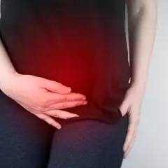 Donna con le mani sull'addome, evidenziato da un bagliore rosso, che indica dolori ovulazione da 5 giorni.