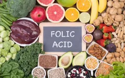La **folina a cosa serve**? È essenziale per la crescita cellulare. L'immagine mostra alimenti ricchi di folati: verdure a foglia verde, fegato, agrumi, legumi e frutta secca.