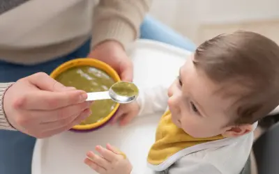 Bambino curioso assaggia la sua prima pappa svezzamento, con un cucchiaino pieno di verdure.