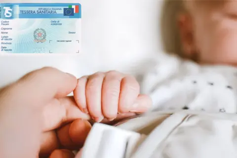 La tessera sanitaria con il codice fiscale di un neonato, tenuta dalla mano di un adulto.