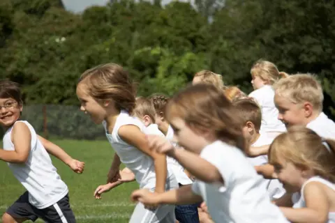 Bambini in corsa su un prato verde, felici di fare sport.