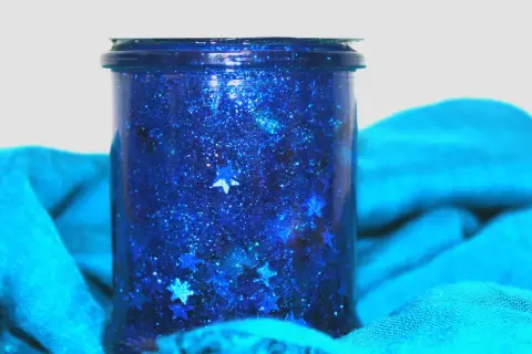 Barattolo della calma blu scintillante con stelle cadenti, avvolto in un tessuto turchese.