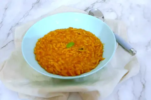 Un piatto di pastina al pomodoro, gustosa e profumata, guarnita con una fogliolina verde.
