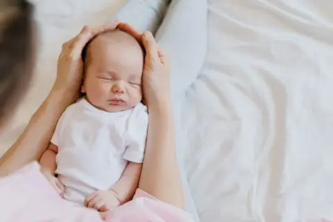 Mani che accarezzano la testa di un neonato addormentato. Il dolce rumore phon bambini lo culla nel sonno.