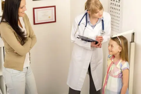 Medico misura altezza bambina, madre osserva. Valutazione del rapporto altezza peso per la crescita.