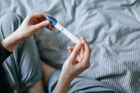 Mani che tengono un test di gravidanza, sperando in trucchi per rimanere incinta del secondo figlio.