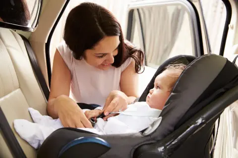 Mamma controlla la posizione corretta neonato nell'ovetto, assicurandosi che sia ben allacciato per un viaggio sicuro.