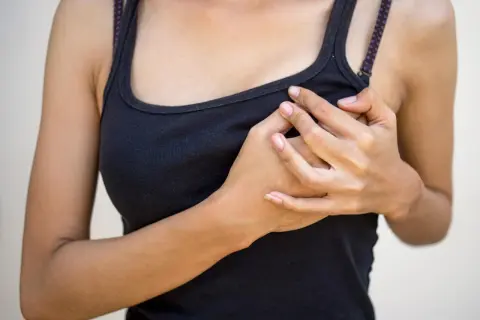 Mani che stringono il seno gonfio senza ciclo, un disagio che preoccupa.
