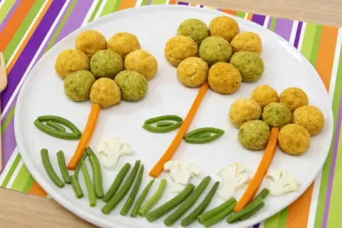 Fiori colorati fatti con ceci e patate, con gambi di carota e foglie di fagiolini.
