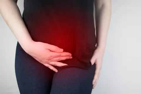 Donna con mani sull'addome, evidenziato da un bagliore rosso, che suggerisce un disagio come la pancia gonfia ovulazione.