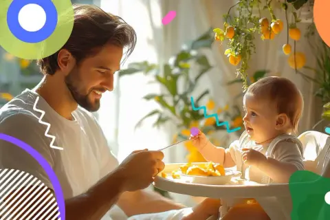 Padre sorridente nutre un neonato di 10 mesi seduto sul seggiolone, con cibo sul vassoio.