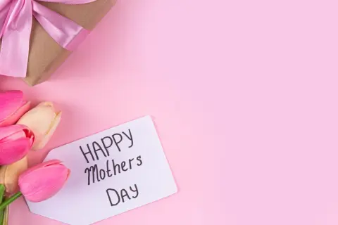 Un regalo incartato con un fiocco rosa e tulipani colorati, pronti per la festa della mamma in Italia.