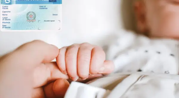 La tessera sanitaria con il codice fiscale di un neonato, tenuta dalla mano di un adulto.