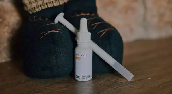 Flacone di vitamina D per neonati con contagocce, accanto a un pupazzo.