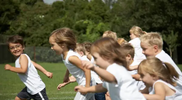Bambini in corsa su un prato verde, felici di fare sport.