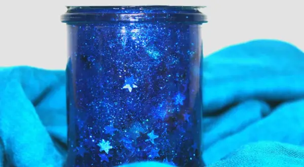 Barattolo della calma blu scintillante con stelle cadenti, avvolto in un tessuto turchese.