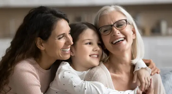 Tre generazioni di donne sorridono felici, un abbraccio che ricorda le più belle canzoni per la festa della mamma.
