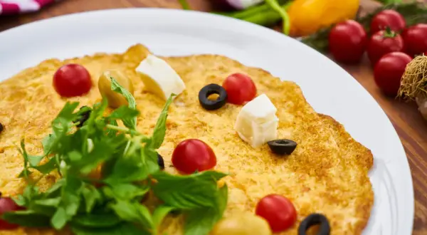 Frittata per bambini, colorata con pomodorini, olive, cubetti di formaggio e rucola. Un piatto gustoso e invitante.