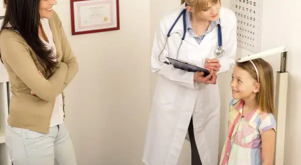 Medico misura altezza bambina, madre osserva. Valutazione del rapporto altezza peso per la crescita.