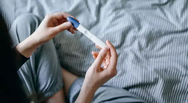 Mani che tengono un test di gravidanza, sperando in trucchi per rimanere incinta del secondo figlio.