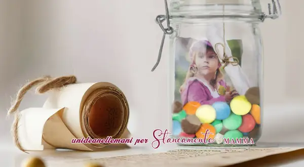 A rolled scroll tied with twine and a glass jar filled with colorful candies and a child's photo.