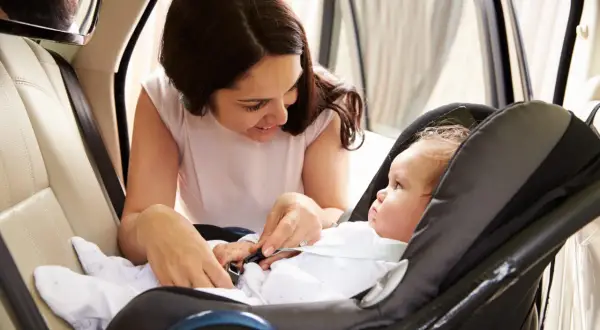 Mamma controlla la posizione corretta neonato nell'ovetto, assicurandosi che sia ben allacciato per un viaggio sicuro.