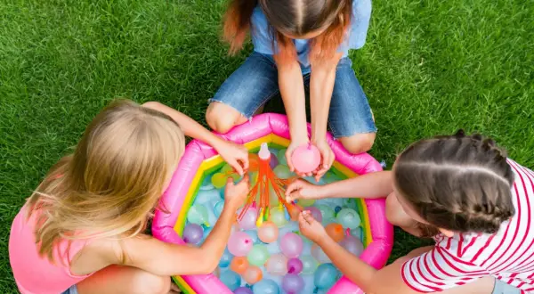 Bambine si divertono con palloncini d'acqua, perfetti giochi per feste di compleanno 7-8 anni.