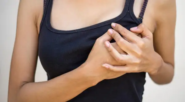 Mani che stringono il seno gonfio senza ciclo, un disagio che preoccupa.