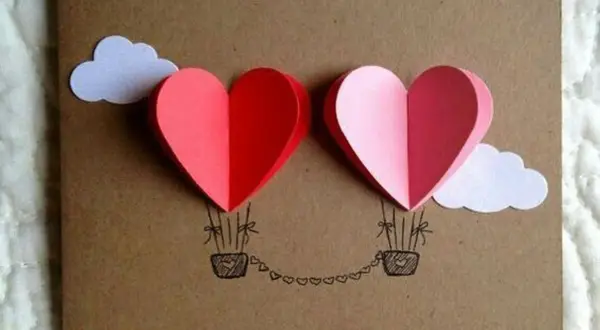 Lavoretto festa della mamma infanzia: due mongolfiere a forma di cuore rosse e rosa, con nuvole bianche e cesti disegnati.