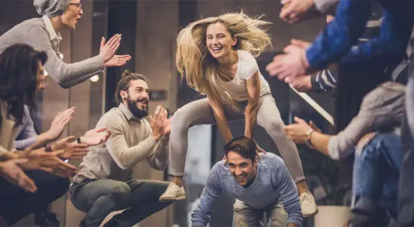 Un gruppo di amici si diverte con giochi da fare in gruppo seduti senza niente, tra risate e applausi.