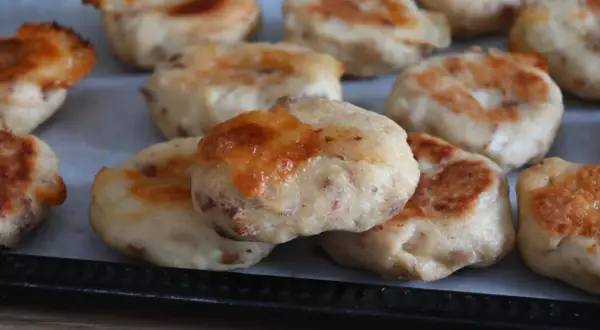 Deliziose polpette di pollo appena sfornate, dorate e con formaggio filante, pronte per essere gustate.