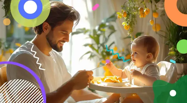 Padre sorridente nutre un neonato di 10 mesi seduto sul seggiolone, con cibo sul vassoio.