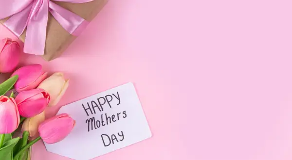 Un regalo incartato con un fiocco rosa e tulipani colorati, pronti per la festa della mamma in Italia.
