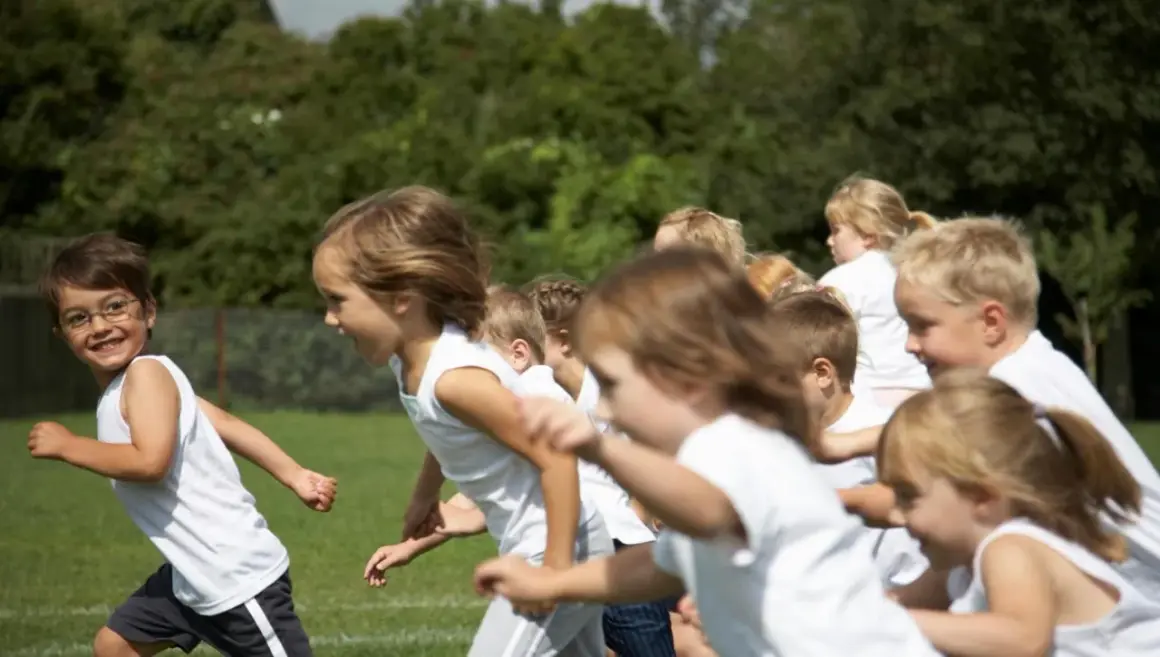 Bambini in corsa su un prato verde, felici di fare sport.