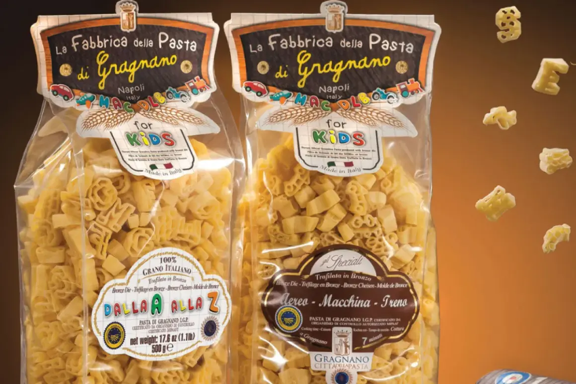 Due confezioni di pasta per bambini, una con lettere e l'altra con aerei, macchine e treni, prodotte a Gragnano.