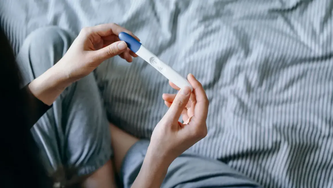 Mani che tengono un test di gravidanza, sperando in trucchi per rimanere incinta del secondo figlio.